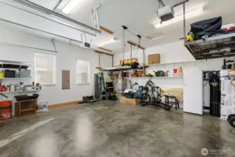 The oversized double garage features high ceilings with windows along the side and overhead for so much light. Two hanging storage racks and built-in shelving, as well as a whole house water purification system (along the back wall) complete the package.