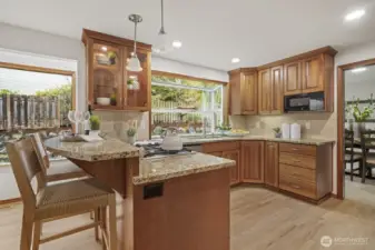 Chef's kitchen with custom cherry cabinets, granite counters, gleaming hardwoods, and greenhouse window.