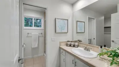 Primary bath highlighted by tile floors and countertops and freshly painted cabinetry.