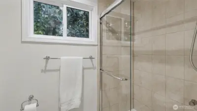 New large glass shower in primary suite with well positioned window to let in light yet maintain privacy