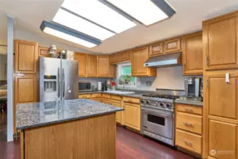 Kitchen with skylights, large granite island & stainless steel appliances.