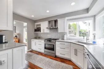 A custom chef’s kitchen anchors the home with quartz countertops, premium appliances, custom cabinetry, and electronic blinds over the sink