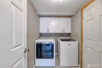 Well appointed laundry room features top-end appliances, a gas dryer, and upper cabinetry for added storage.
