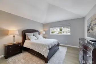 Serene primary bedroom features vaulted ceilings, elegant engineered hardwood flooring, and abundant natural light