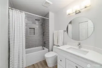 Stylish upper guest bathroom features a modern vanity, sleek lighting, and a tiled shower with built-in inlay
