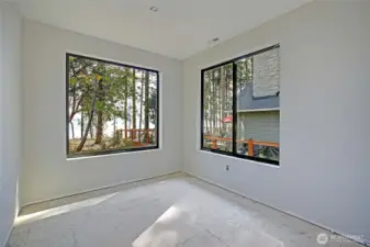 Bright home office with large windows capturing serene water views, perfect for work or quiet focus.
