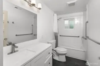 Recently updated bathroom with accessibility grab bars in walls and in the shower, offering modern design, safety, and ease of use