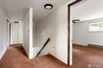 Top of the stairs, with bedroom 1 on the right, and the hallway leading to the primary suite and a full bathroom.