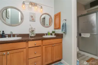 Main bedroom with double sinks and walk in 3/4 shower with tile surround.