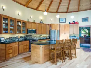 Kitchen, with polished granite island, cherry Shaker-style cupboards, and stone mosaic