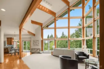 The kitchen flows seamlessly into a sunlit living room with floor-to-ceiling windows.