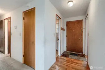 The door to the furthest right is toward the kitchen, the next one is the entry door, with security hole.  to the left of that is the guest bathroom.  then down the hall is a coat closet, then the full bathroom then a linen closet.  the thermostat is on the wall.