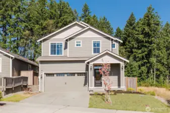 Driveway and garage view with mature trees framing the property.