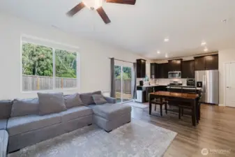 Spacious living room with ceiling fan and open flow to kitchen.