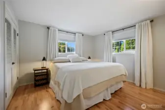 The primary bedroom is light and fresh with the gorgeous wood floors and two windows. Pull down shades and lovely curtains provide both a light barrier and style.