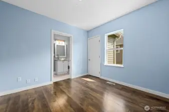 Freshly painted in soft blue tones, this cozy bedroom features warm wood flooring, a closet, and direct access to a private bath.