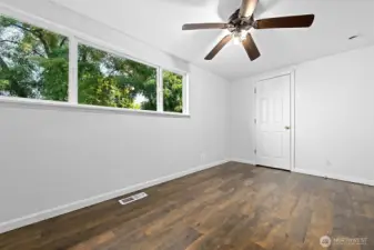 Bright and airy with large windows, this cozy bedroom is finished with rich wood flooring and a ceiling fan for comfort.