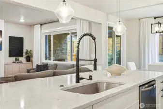 Kitchen island with seating and pendant lighting overlooking the living area in this Covington WA home for sale, creating a central gathering space.