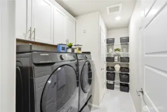 Dedicated laundry room with washer and dryer, built in shelving, and storage space inside this Covington WA home for sale built in 2020, offering convenience for everyday living.