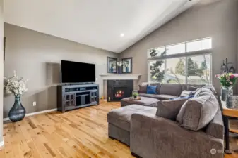The light-filled living room is a haven of comfort with its high airy ceilings balanced by the warmth of hardwood flooring and a cozy gas fireplace.