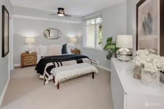 Luxurious and spacious primary bedroom features a large picture window looking out to the deck and beyond. Ceiling fan, large walk-in closet and en suite complete the space.