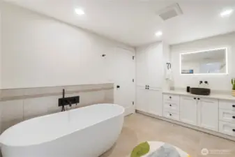 Tons of beautiful cabinetry, a lighted hotel mirror plus tile flooring & surround accents the lower level bath