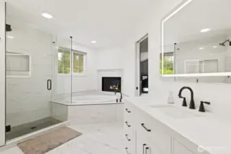 Newly remodeled, the ensuite features a designer-tiled shower with seamless glass enclosure and soaking tub in front of the fireplace.