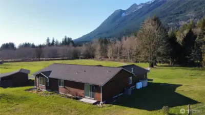 Aerial view of back of the house, looking toward 371st Ave NE, and the mountains in the background.