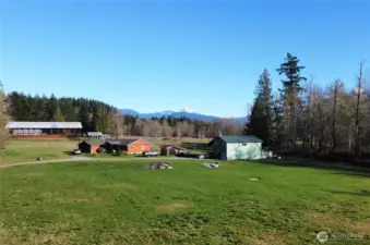 Aerial view of house and outbuildings, looking east.  Equestrian arena in background is located on neighbor's property.