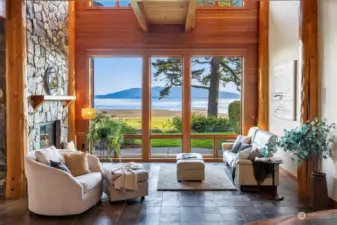 Upon entering, the Great Room's window wall beautifully frames your first glimpse of the stunning view. Slate flooring, peeled Douglas Fir tree posts, Fir trim and an artisan stone fireplace accentuate the space.