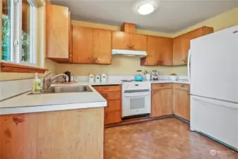 Kitchen with lots of cabinets for storage and supplies, stainless steel sink and large refrigerator.