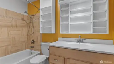 The bathroom has a large counter and a ton of shelving.
