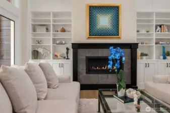 The living room feels both dramatic and inviting, with soaring ceilings, a gas fireplace for cozy evenings, and direct access to a spacious deck that extends the living space outdoors—perfect for entertaining, dining al fresco, or simply enjoying the peaceful natural surroundings.