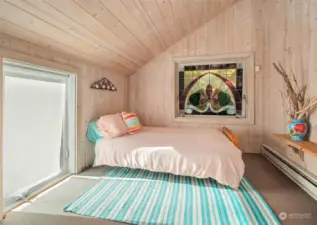 One of three bedrooms on the upper level with western window and north-facing stained glass window.