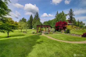 A view of the swinging bench. The pathway leads to a small bridge which crosses the creek water feature.