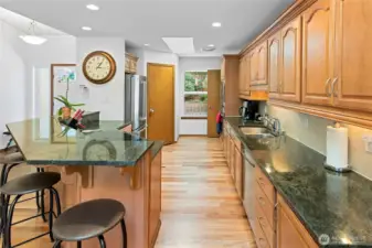 Spacious Kitchen with plenty of storage and pantry.  Slab counters, wood floors, under cabinet counter lighting.