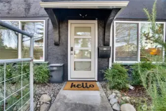 A glass front door, modern windows, and vibrant landscaping create a welcoming first impression.