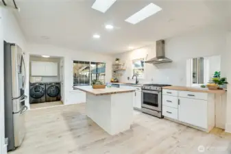 The updated kitchen features butcher block counters, stainless steel appliances, a breakfast bar island, and skylights that keep the space light and bright. Be sure to note the nearby laundry area with extra storage.