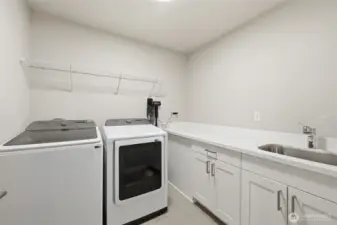 Convenient upstairs laundry with sink, storage and folding counter.