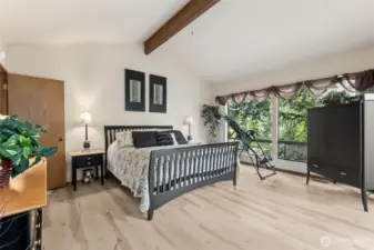 Wall of windows opens large primary bedroom to the outdoors and your private deck.