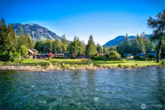 From the cool currents of the Skykomish, look back at River House Retreat nestled on its grassy rise—75 feet of prime Cable Hole frontage, framed by the Cascades and steeped in serenity. In Big Bend, few homes offer this much access, privacy, and postcard-worthy perspective.