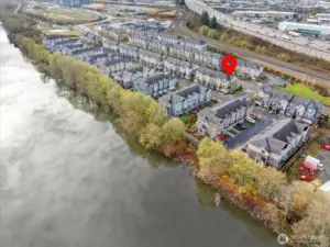 Displays the home’s corner placement with nearby green space and riverside trails in view