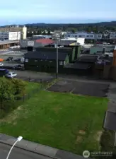 Green frontage along W. 1st Street with 8 paved parking spaces in back, off alley entrance.