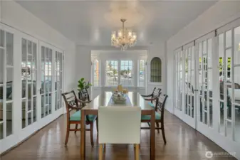 Sun-drenched dining room framed by elegant French folding doors and a classic bay window
