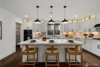Kitchen Island with Pantry View: Large center island with pendant lighting provides seating and storage while overlooking the walk-in pantry. Perfect for hosting, this layout keeps everything within easy reach.    Photos are from the model home at Foxmoore and for visualization purposes only. Plans, colors, building orientation, finishes, home outlook, and other details can and WILL vary.