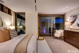 Dramatic twilight photo of the primary bedroom with the Great Wheel illuminated through the sliding glass door.