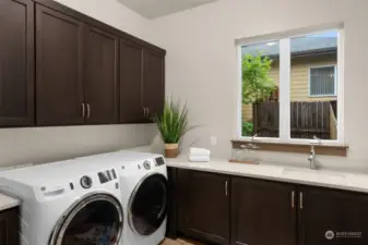 Laundry room has a sink and plenty of cabinets and countertop space