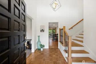The vaulted foyer features wood floors  and a beautiful wood and iron staircase