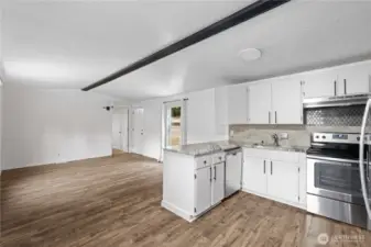 Open floor plan with laminate floors, granite countertops, and stainless steel appliances