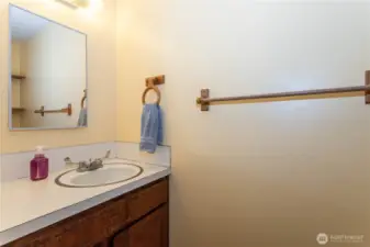 This convenient half bath is tucked into the home for easy access. With a simple vanity, mirror, and warm wood cabinetry, it offers practicality in a compact space. Neutral finishes make it easy to update or personalize. Perfect for guests or quick use, it adds functionality to the home’s layout and ensures comfort for everyday living.